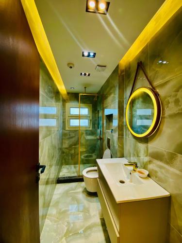 a bathroom with a sink and a toilet and a mirror at Luxury 3 bedroom apartment in Banī Ghālib