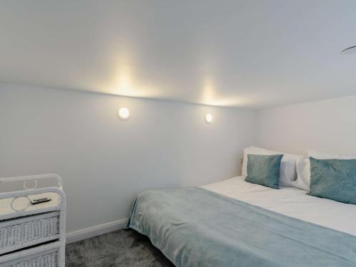 a white bedroom with a bed with blue pillows at 1 Bed in Tresaith 89316 in Penbryn