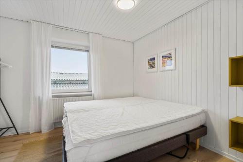 ein weißes Schlafzimmer mit einem Bett und einem Fenster in der Unterkunft 8817 Hvide Sande - Mågevej 2 in Hvide Sande