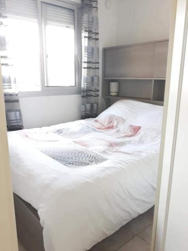a white bed in a bedroom with a window at Soleil d'or à St Aygulf in Fréjus