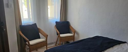 a room with two chairs and a bed and a window at Beachfront Habitat in Flic-en-Flac