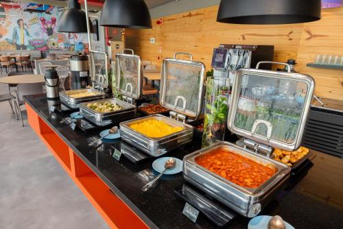 a buffet with several trays of food on a counter at Ibis Budget Guarulhos Aeroporto in Guarulhos