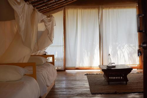 a bedroom with two beds and a table in front of a window at Eco Lodge Mancora in Máncora