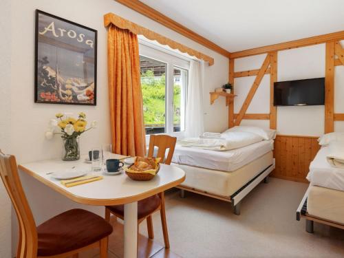 a room with two beds and a table and a desk at Apartment Promenade - Utoring-5 by Interhome in Arosa