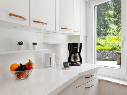 a white kitchen with a bowl of fruit on a counter at Apartment Promenade - Utoring-5 by Interhome in Arosa