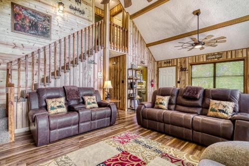 a living room with two leather couches and a staircase at Heavenly Gaze in Pigeon Forge