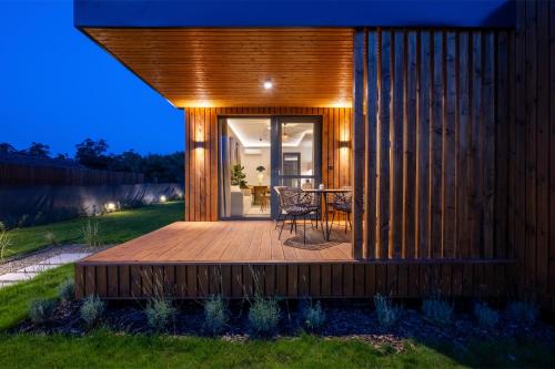 a wooden deck with a dining table in a backyard at Natur Harmony Tiszafüred in Tiszafüred