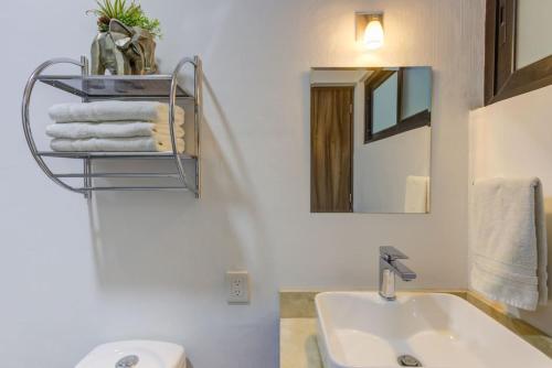 een witte badkamer met een wastafel en een spiegel bij La Cruz Encantada 1A in Cruz de Huanacaxtle