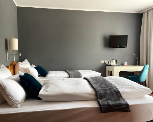 um quarto com 2 camas e uma televisão na parede em Hotel Tari em Würzburg