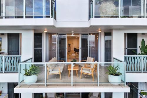 Un balcón de una casa con una mesa y sillas. en Skyview Luxe at Marquis, en Cairns