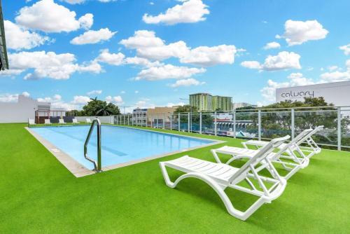 a swimming pool with lounge chairs on the roof of a building at Skyview Luxe at Marquis in Cairns