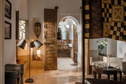 uma sala de estar com uma porta que leva a uma sala com uma mesa em Riad Jaaneman em Marraquexe