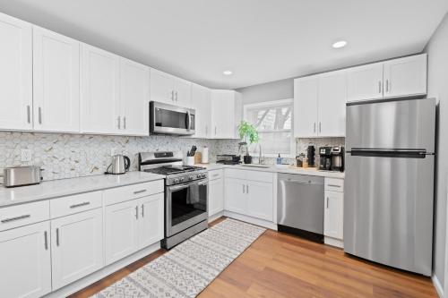 a kitchen with white cabinets and a stainless steel refrigerator at Cozy Home, 17 min from NYC, 2 Parking Spaces in Ridgefield Park