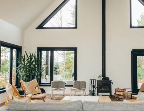 a living room with a couch and chairs and windows at Forest Edge Escape at Dimensions - Cabin Sixteen in Algonquin Highlands
