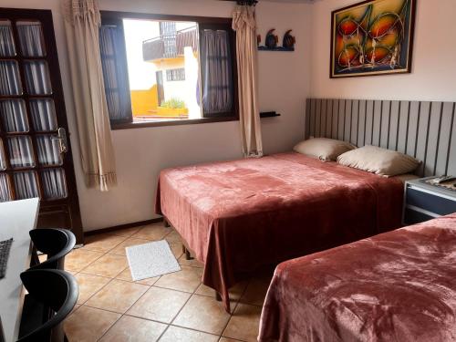 a hotel room with two beds and a window at Flat Pé na Areia Cabo Frio in Cabo Frio