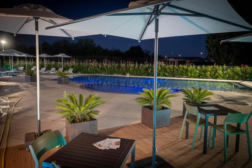 a table and chairs under an umbrella next to a pool at Ile Hotel in Peschiera del Garda
