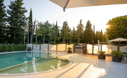 a pool in a backyard with a fence and trees at Ile Hotel in Peschiera del Garda