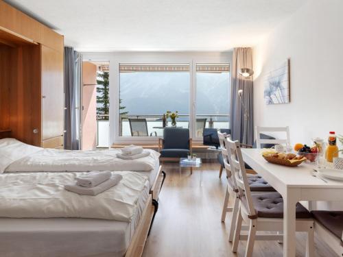 a hotel room with two beds and a table and chairs at Apartment Promenade Apt 109 & Apt 110 by Interhome in Arosa