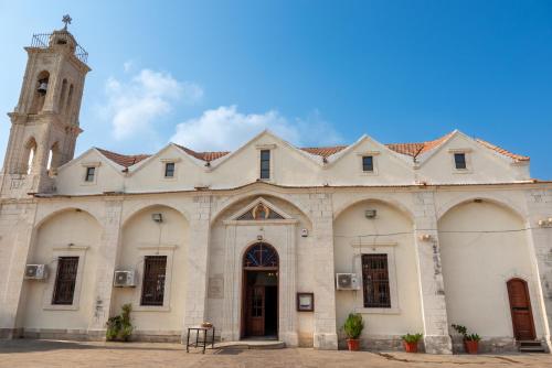 a large white building with a clock tower at Casa Piedra, Hidden Gem, Jacuzzi, BBQ, Patio in Monagroulli in Monagrulli