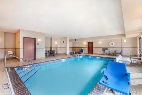 a pool in a hotel with blue chairs and tables at Clarion Pointe Sioux Falls Airport in Sioux Falls