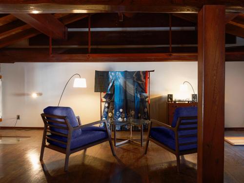 two blue chairs and a glass table in a room at 泊まれる文化交流施設 盆宿U bon-yadoU in Nishimonai