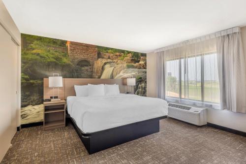 a hotel room with a bed and a waterfall mural at Clarion Pointe Sioux Falls Airport in Sioux Falls