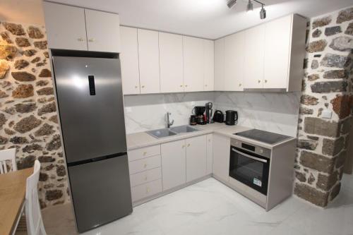 a kitchen with white cabinets and a stainless steel refrigerator at Elysian Stone Apartment I in Litochoro