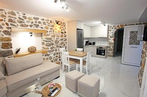a living room and kitchen with a stone wall at Elysian Stone Apartment I in Litochoro