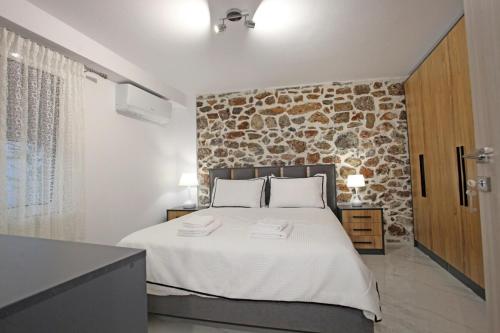 a bedroom with a large bed with a stone wall at Elysian Stone Apartment I in Litochoro