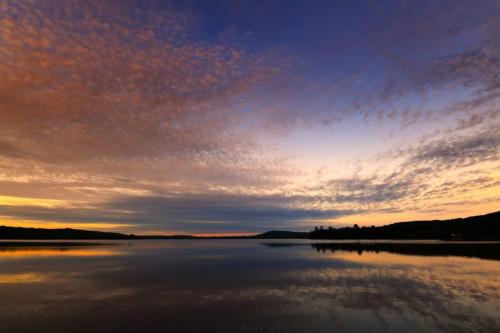 a sunset over a large body of water at Nourish and Reset at Dimensions - Cabin Ten in Algonquin Highlands