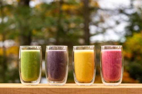 four glass cups filled with different colored liquids at Sauna Trail Hideaway at Dimensions - Cabin Seven in Algonquin Highlands