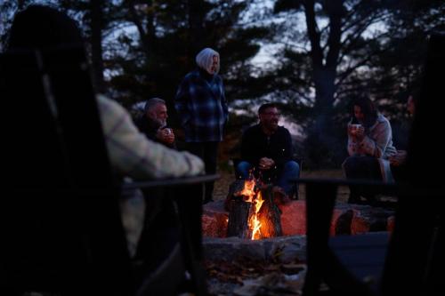 a group of people sitting around a camp fire at Sauna Trail Hideaway at Dimensions - Cabin Seven in Algonquin Highlands
