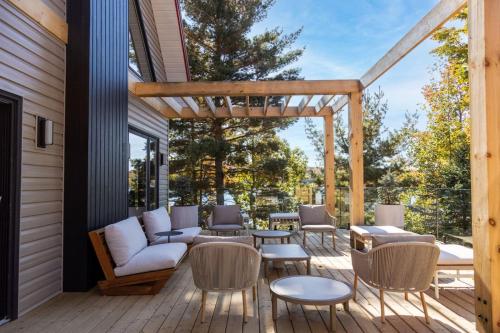 a patio with a couch and chairs on a deck at Wildflower Rest at Dimensions - Cabin Fifteen in Algonquin Highlands