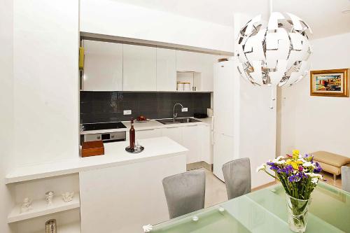a kitchen with white cabinets and a vase of flowers at Apartments Blue Horizon in Mlini