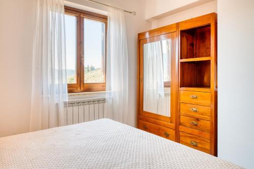 a bedroom with a wooden cabinet and a window at Umbria Casavacanze in Montefranco