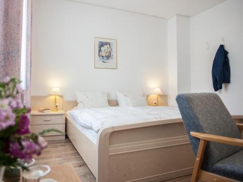 a small bedroom with a bed and a chair at Pension Haus Brieden in Winterberg