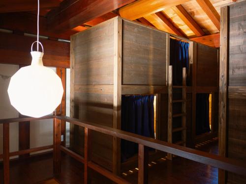 a room with a wooden wall and a light and a ladder at 泊まれる文化交流施設 盆宿U bon-yadoU in Nishimonai