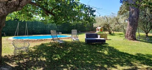 une cour avec deux chaises et une balançoire au bord d'une piscine dans l'établissement Le Mélomane - Maison climatisée avec jardin clos, à Montfrin