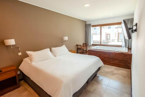 a bedroom with a large white bed and a window at Rincón del Duende Resort y Spa de Mar in Mar de las Pampas