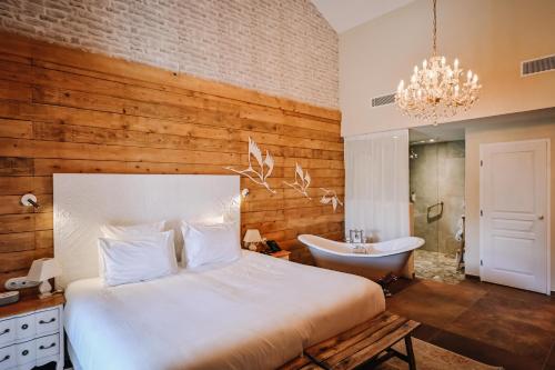 a bedroom with a bed and a tub and a sink at Le Hameau Des Pesquiers Ecolodge & Spa, Curio Collection By Hilton in Hyères