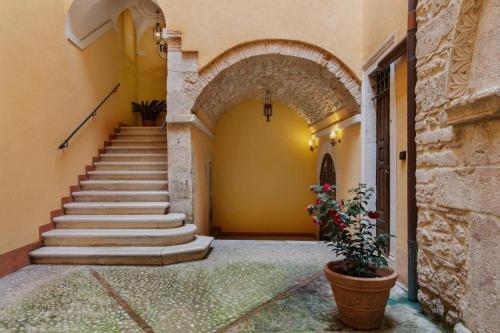 an entrance to a building with a stairway with a plant at Palazzo Cappa-Affitti Brevi Italia in LʼAquila