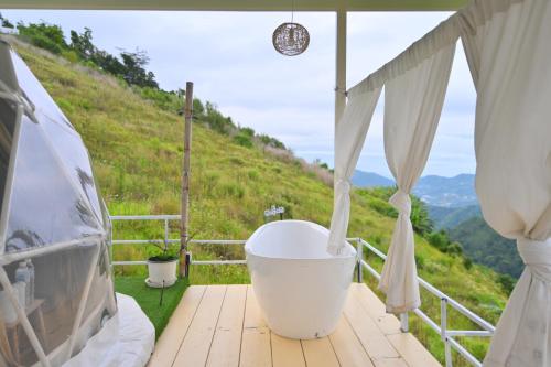a bath tub on a deck with a view of a hill at ภูวินคาเฟ่ โฮมสเตย์ Phuwin Homestay Monjam in Mon Jam