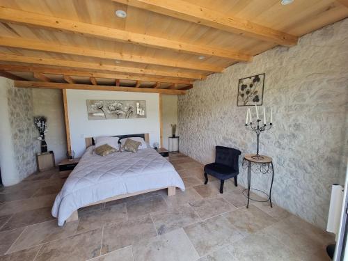 une chambre avec un grand lit et une chaise dans l'établissement Les gites du Treil - 2 Grandes piscines privées- 9 chambres - 20 personnes, à Courbiac