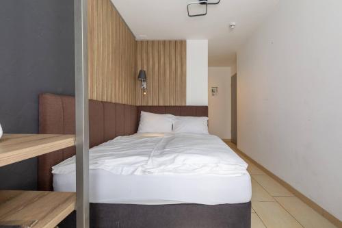 a bed in a small room with white sheets at Nani City Hotel in Zürich
