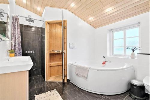 a white bathroom with a tub and a sink at 362-Hvide-Sande-Fyrmarken-35 in Hvide Sande