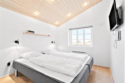 a white bedroom with a bed and a flat screen tv at 362-Hvide-Sande-Fyrmarken-35 in Hvide Sande