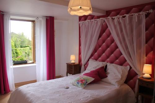 a bedroom with a large bed with a red headboard at gite de la ruelle des messes in LʼÉchelle