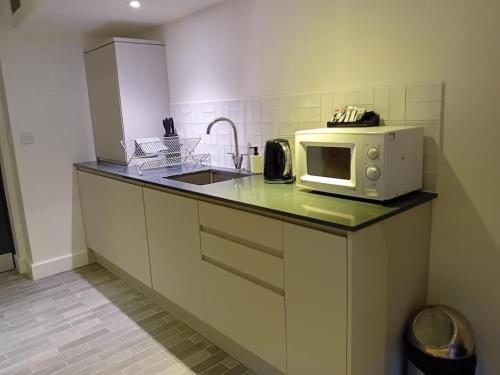a kitchen with a sink and a microwave on a counter at Ty Canol Studios in Llithfaen