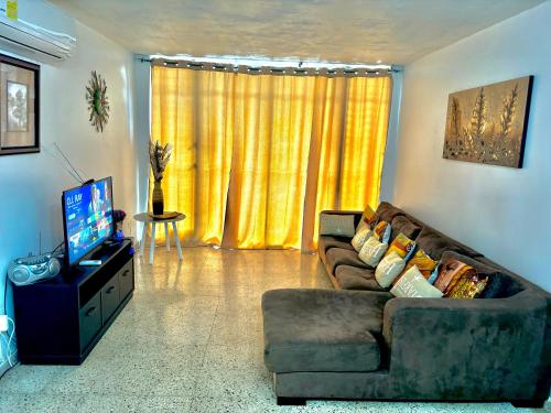 a living room with a couch and a television at Perfect Large Home for Groups & Families in Ponce in Ponce