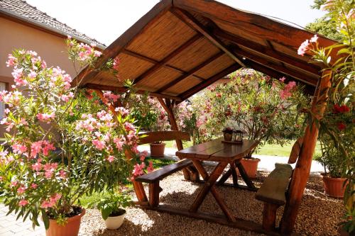 a wooden pavilion with a picnic table and flowers at Lak6 Apartment in Mórahalom
